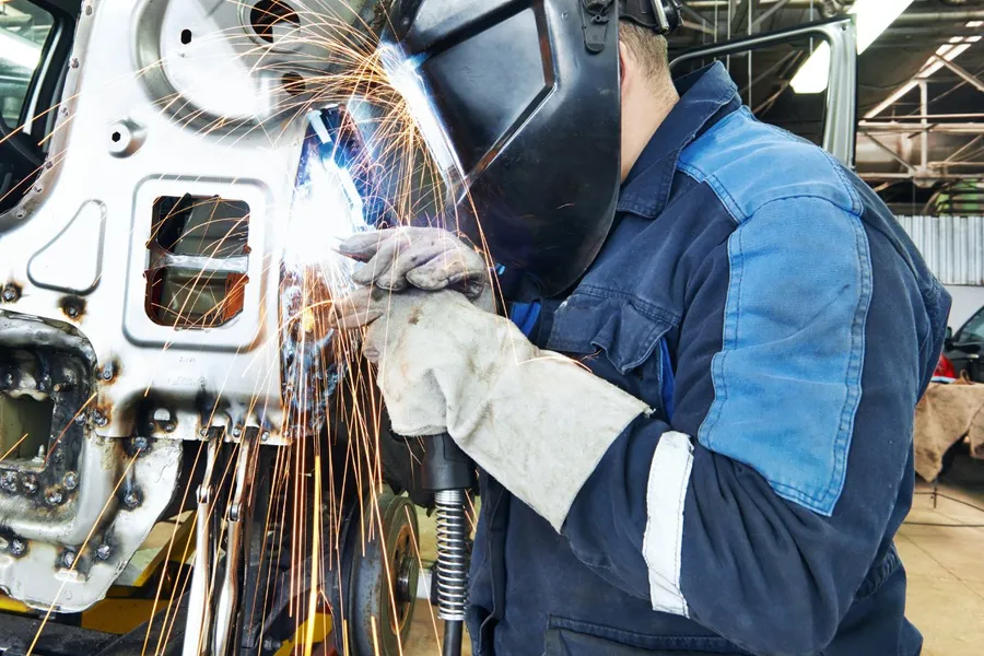 Technician welding a car body panel in the workshop