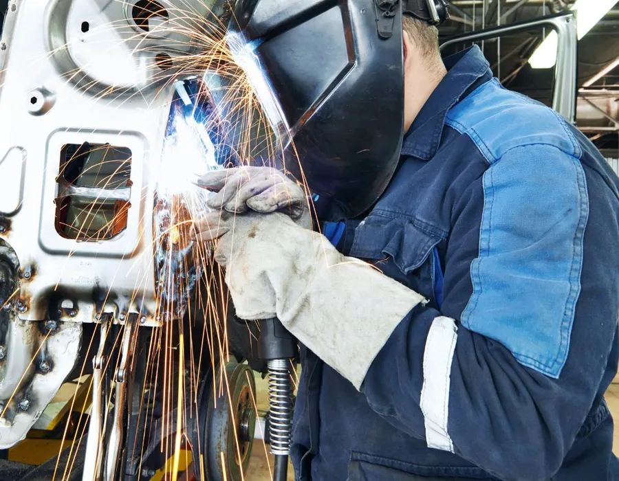 Technician welding a car body panel in the workshop
