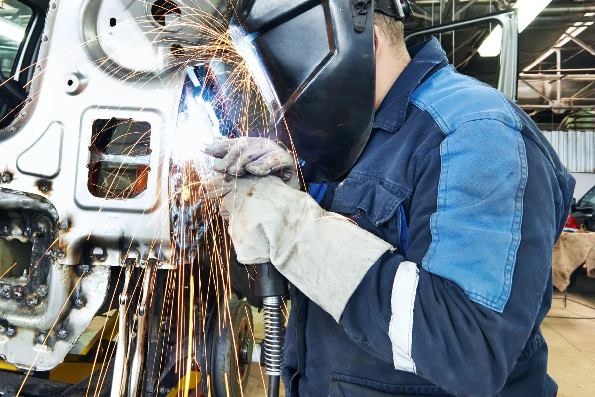 Technician welding a car body panel in the workshop