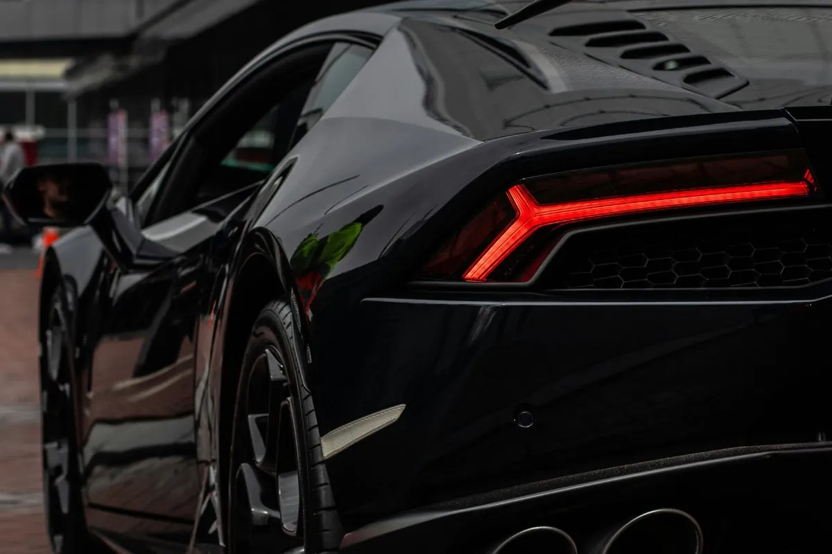 Rear detail of a black Lamborghini supercar with its red tail light lit